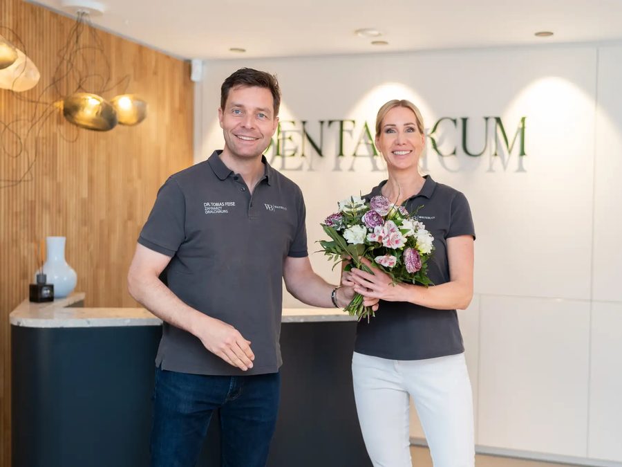Dr. Feise überreicht einer Mitarbeiterin einen Blumenstrauß am Empfang